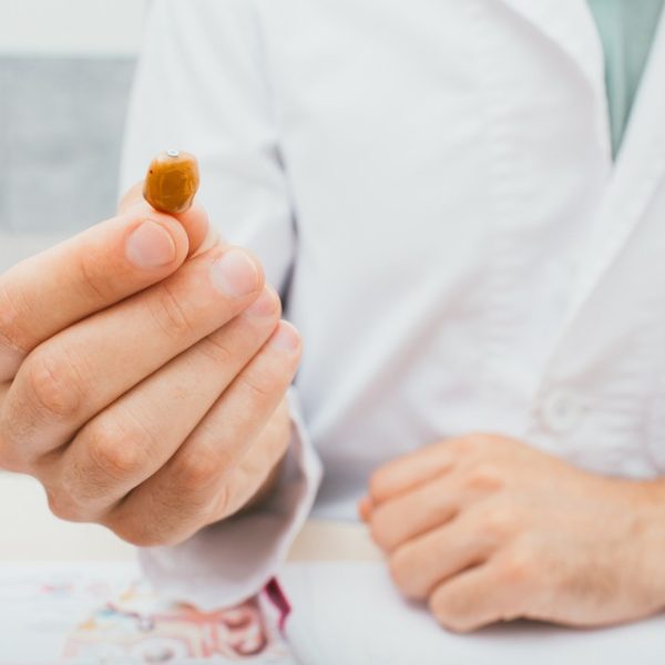 hearing-specialist-holding-a-tan-colored-hearing-aid